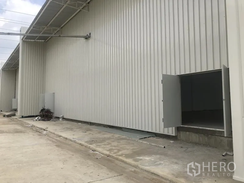 工厂 出租在Khlong Luang, Pathum Thani - 金属覆层仓库侧立面，服务门向通道开启。
