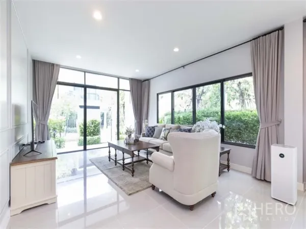 Detached House for rent in Bang Kapi, Bangkok - Sunlit living area with floor-to-ceiling glass, neutral curtains, and greenery outside in a Hua Mak detached house.