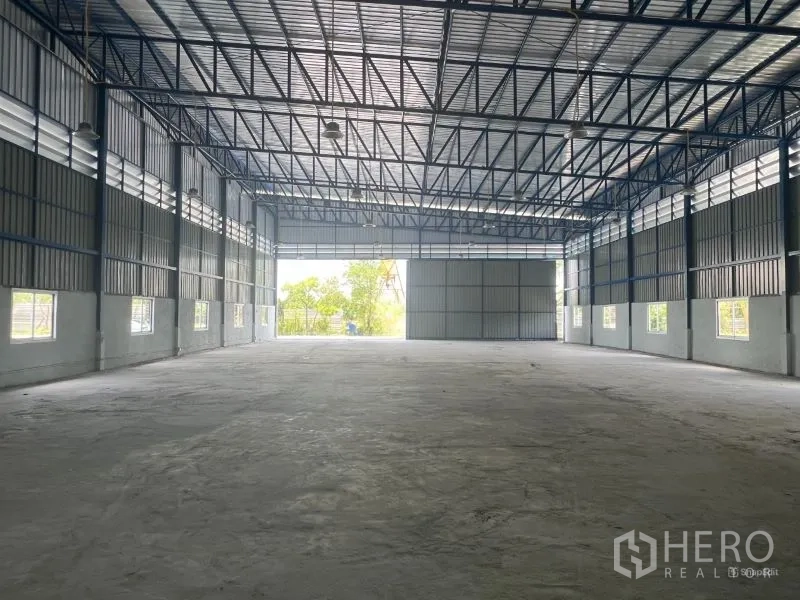 Warehouse for rent in Min Buri, Bangkok - View from the back toward the wide entrance with ventilation louvers and a roller-style door.