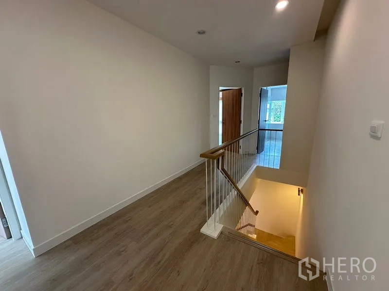 Home Office for rent in Khlong Toei, Bangkok - Upper landing with wooden floors, slim stair railing and a hallway leading to bright rooms.