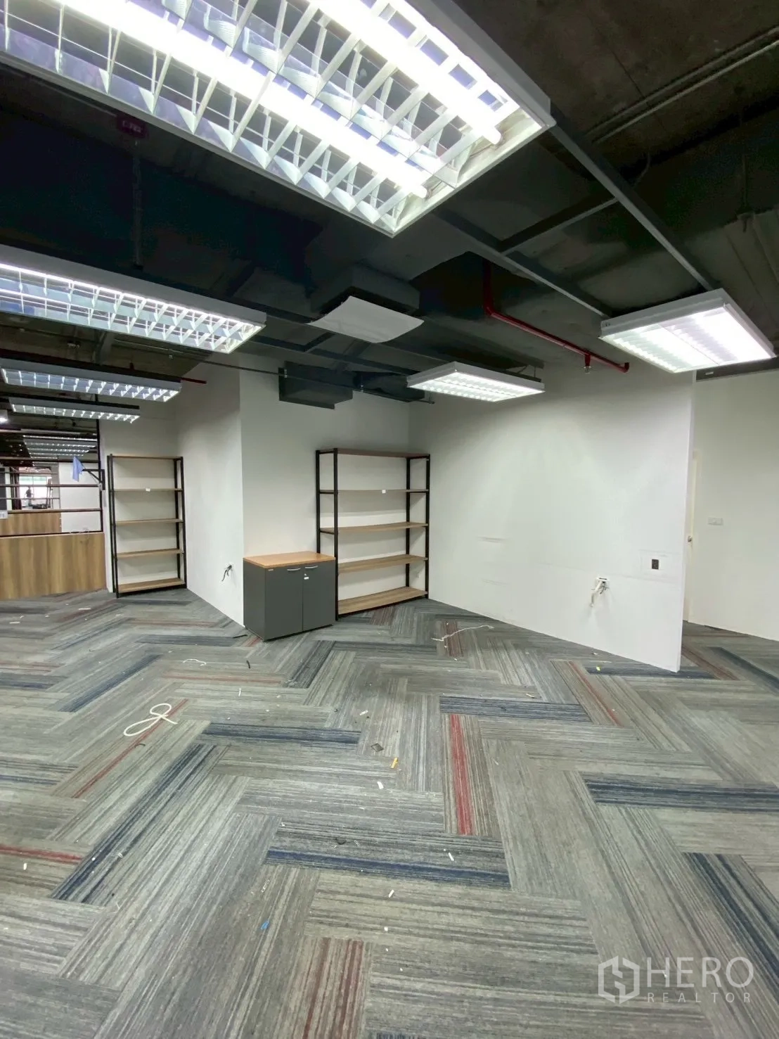 Office Space for rent in Watthana, Bangkok - Corner area with built-in shelving and storage under suspended lighting.