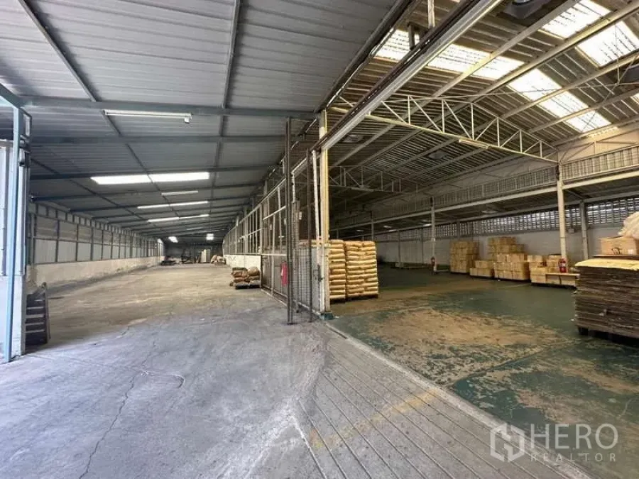 Warehouse for rent in Yan Nawa, Bangkok - Expansive warehouse view with fenced loading area, pallets and durable concrete flooring.