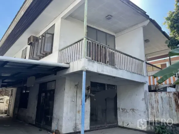 Detached House for sale in Khlong Toei, Bangkok - Close view of an older home showing weathered balcony, sliding glass doors and metal-roof carport.