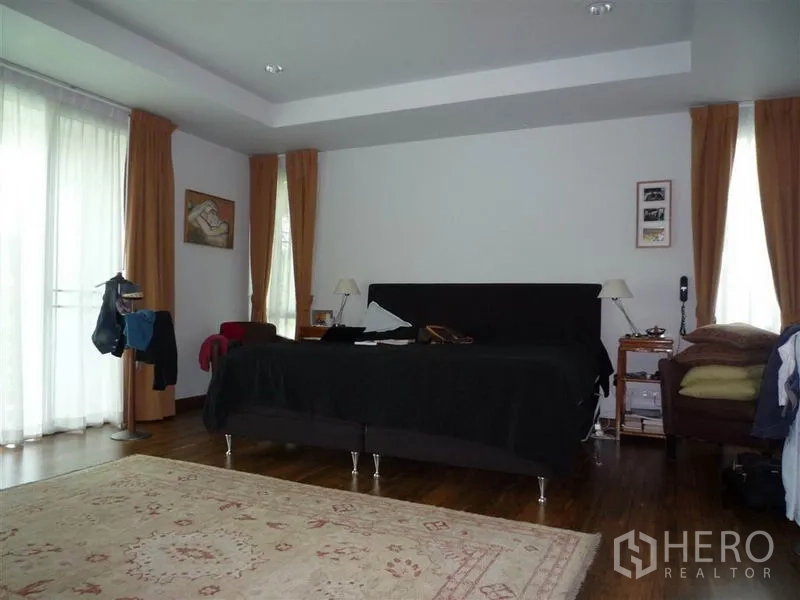 Detached House for rent in Khan Na Yao, Bangkok - Spacious master bedroom with balcony doors, wood flooring and an area rug