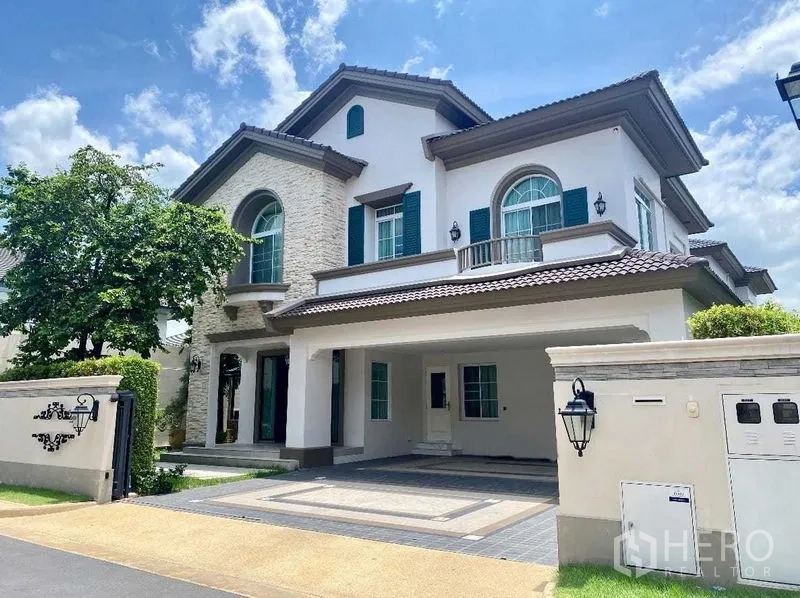Detached House for rent in Bang Khen, Bangkok - Front exterior of a two-storey detached house with arched window, green shutters and a covered carport in Bang Khen, Bangkok.