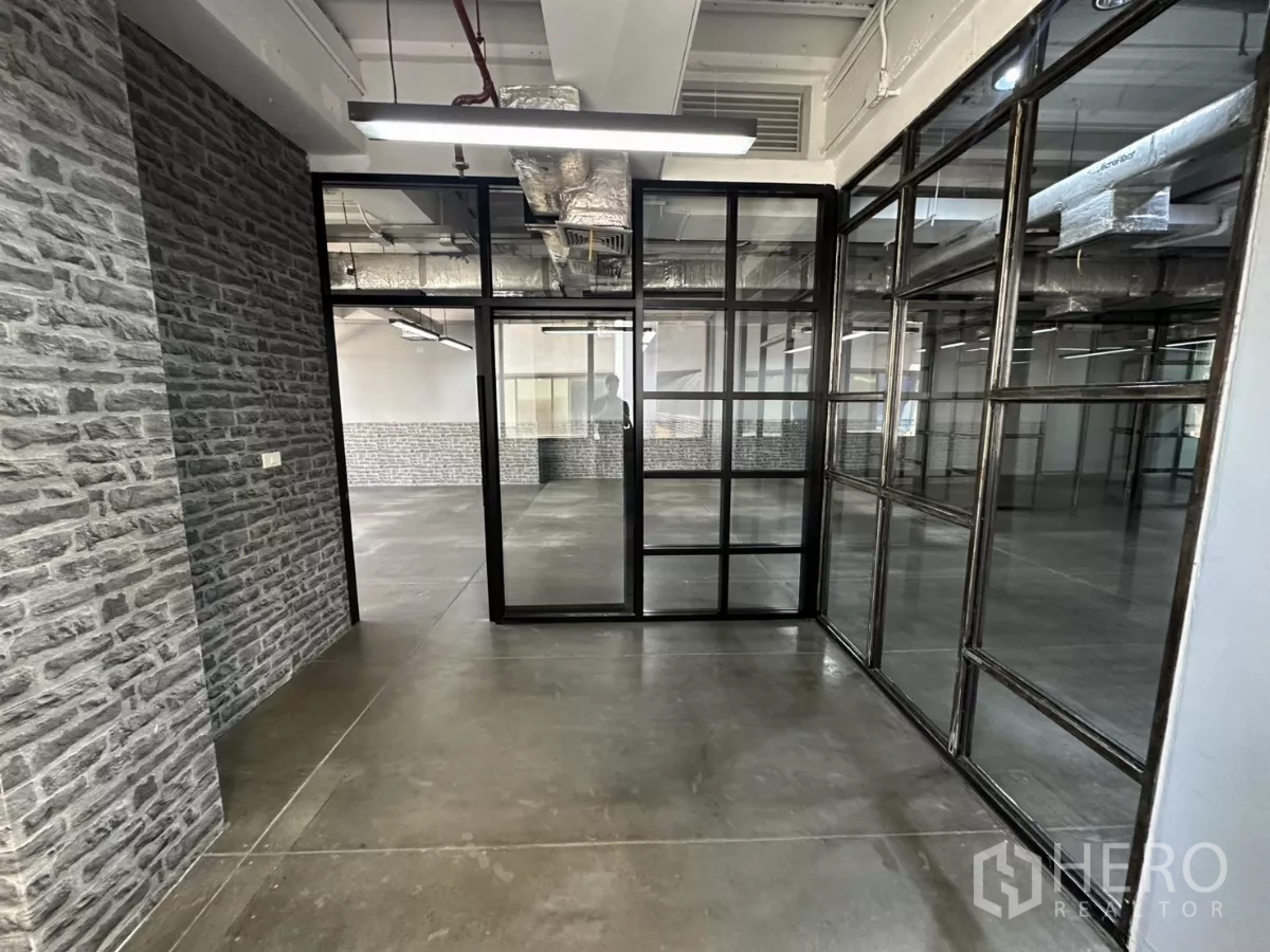 Office Space for rent - Hallway featuring brick-texture walls and black-framed partitions.