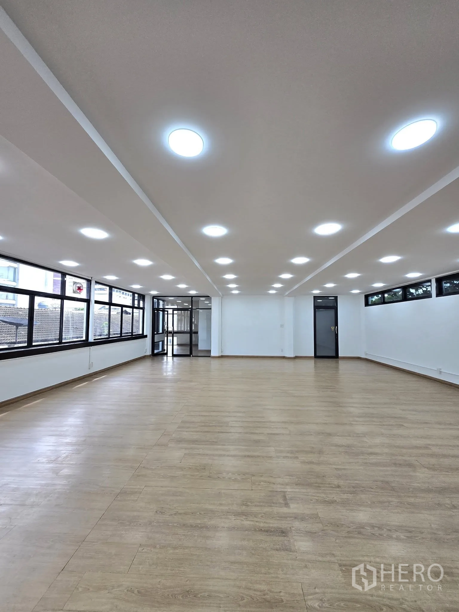 办公室 for rent in Khlong Toei, Bangkok - 狭长开放式工作区，LED照明、木纹地板与黑框窗户及玻璃门。