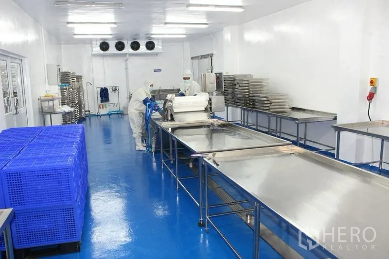 Factory for rent or sale in Krathum Baen, Samut Sakhon - Hygienic production room with stainless tables, trays, and bright overhead lighting.