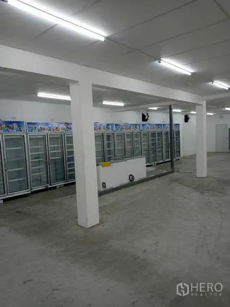 Warehouse for rent in Sathon, Bangkok - Bright warehouse interior with concrete floor, white columns, and a long row of glass-door chillers along the wall.