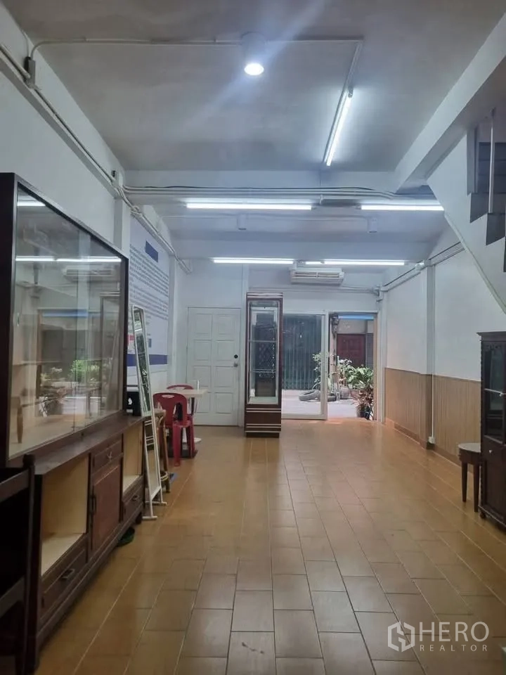 ตึกแถว for rent in Phra Khanong, Bangkok - พื้นที่ชั้นล่างแบบเปิดปูกระเบื้อง ไฟเพดานสว่าง ตู้โชว์ และประตูกระจกด้านหลัง.