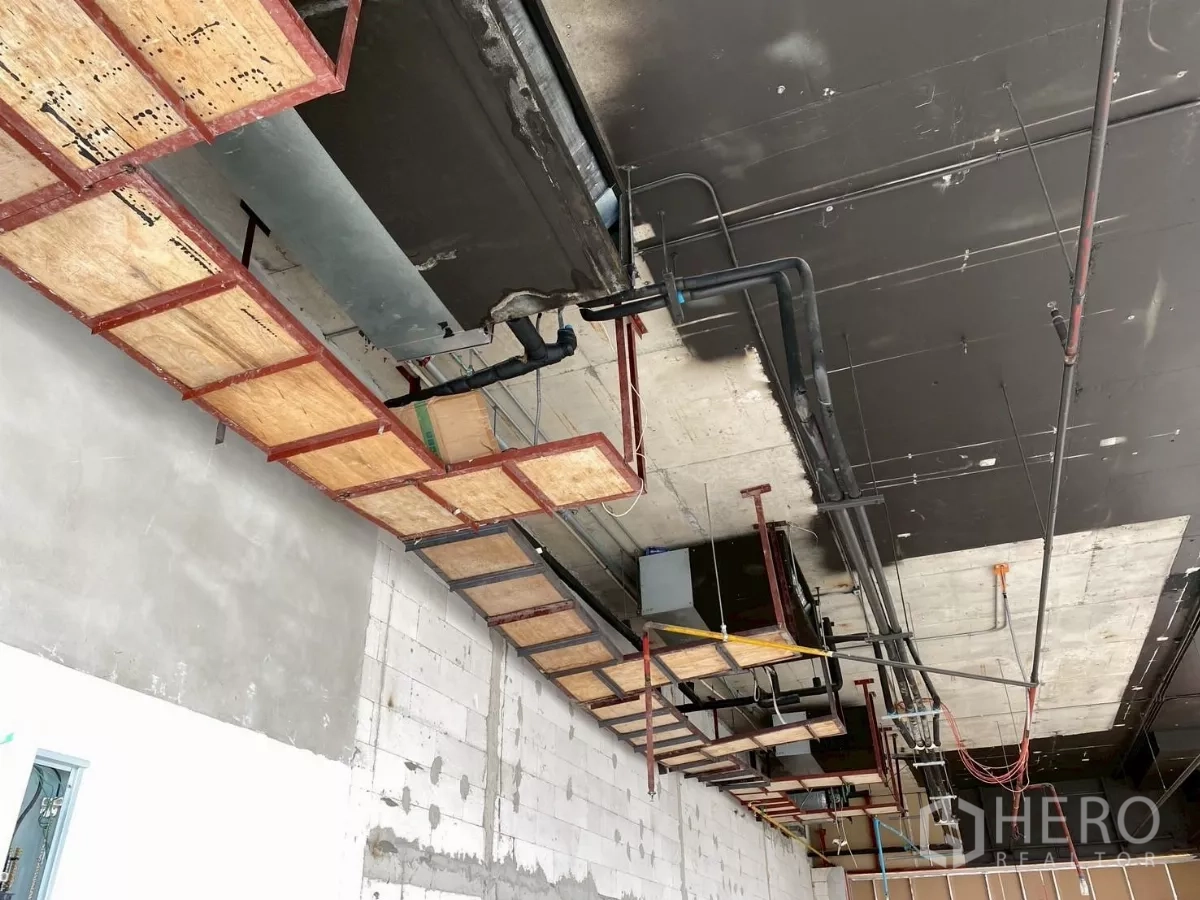 Retail Space for rent - Close-up of exposed ducting, cable trays and fire-safety piping on the ceiling.