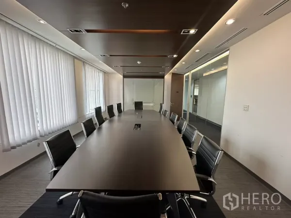 Office Space for rent in Watthana, Bangkok - Large boardroom with a long conference table, around twelve chairs, vertical blinds, wood ceiling accents and glass partitions.
