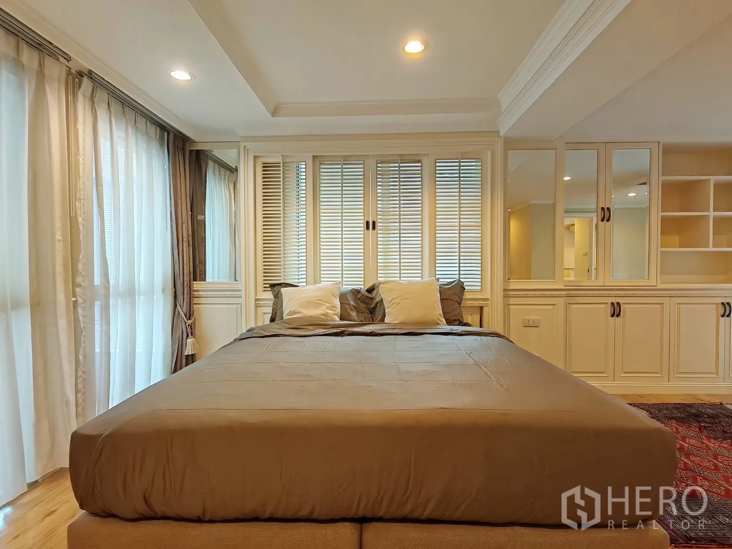 Condominium for rent in Pathum Wan, Bangkok - Close-up of master bed with shutter-style headboard and soft drapes.