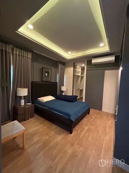 Detached House for rent in Bang Kapi, Bangkok - Guest bedroom with tray ceiling lighting, wood floors, and built-in storage.