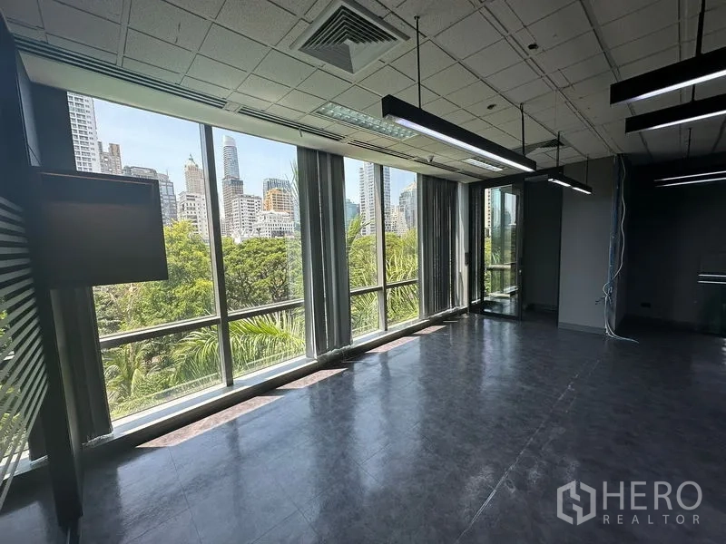 Office Space for rent - Window wall showcasing treetop park views and Bangkok skyline from the office.