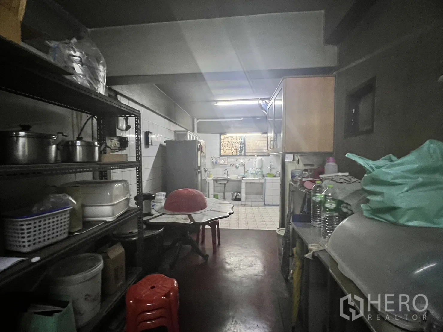 零售空间 出租在Watthana, Bangkok - 后勤备餐区，金属置物架、冰箱与瓷砖水槽，荧光灯照明