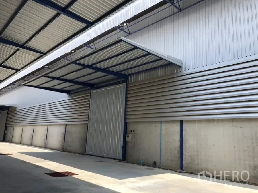 工厂 出租在Lat Lum Kaeo, Pathum Thani - 带雨棚的金属滑动仓门与坚固的混凝土墙面，便于装卸。