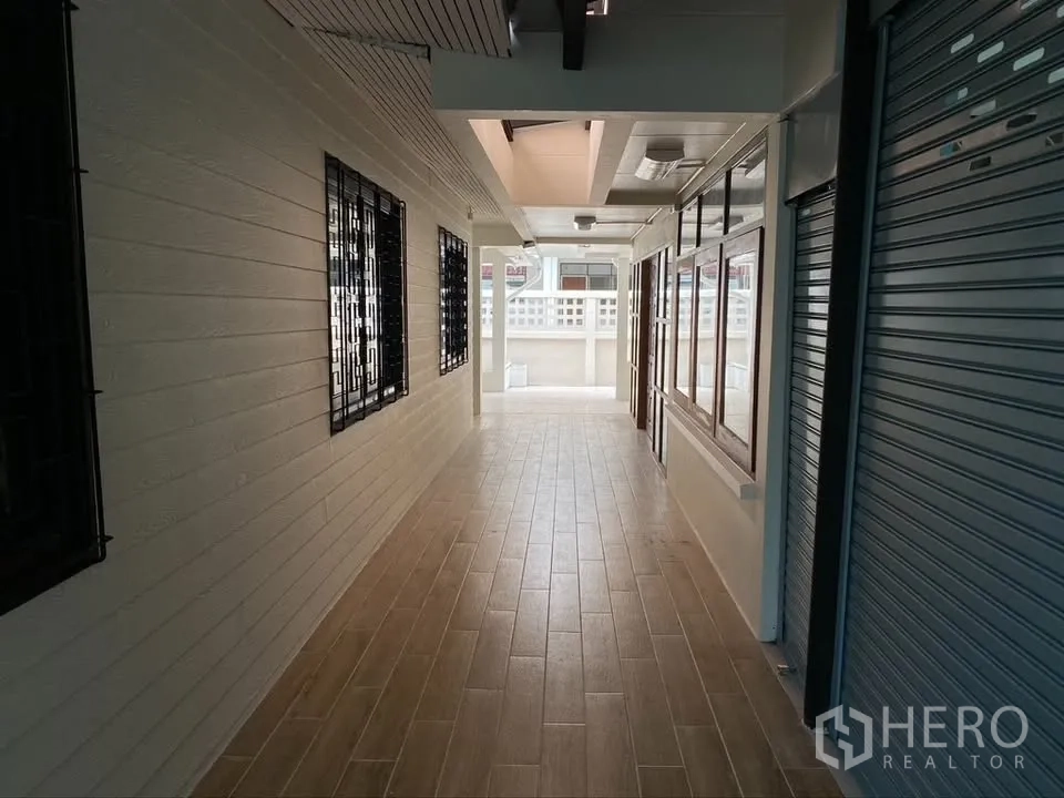 独栋房屋 for rent in Suan Luang, Bangkok - 带顶走廊，木纹地砖、金属卷闸门与窗格护栏。