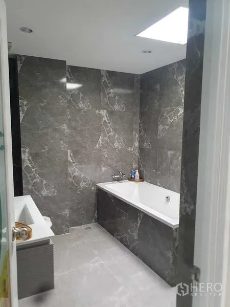 Home Office for rent in Suan Luang, Bangkok - Bathroom with marble-effect tiles and a built-in bathtub.