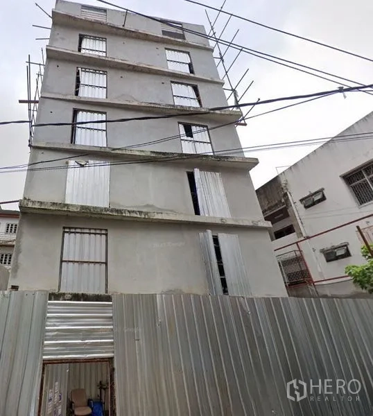 Home Office for rent - Multi-storey concrete home office shell with metal hoarding, viewed from the street.