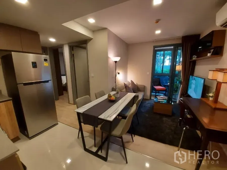 Condominium for rent or sale in Watthana, Bangkok - Open-plan living and dining area with sofa, marble-top table and balcony view in an Ekkamai condo.