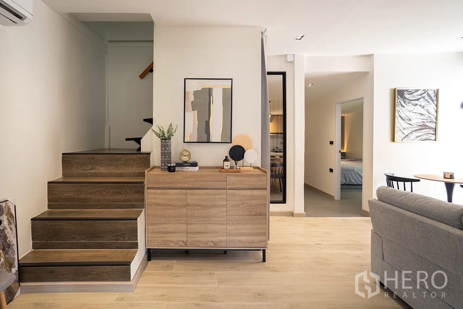 Detached House for rent in Huai Khwang, Bangkok - Wooden staircase next to a console cabinet in the living area.