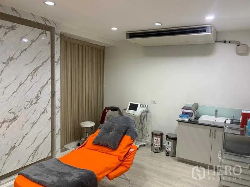 Retail Space for rent in Pathum Wan, Bangkok - Clinic-style room with orange treatment bed, countertop sink, equipment and air conditioning.