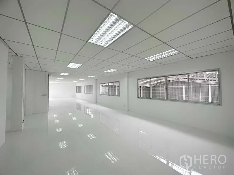 Factory for rent in Pathum Thani - Long open-plan office area with fluorescent lighting and large windows.