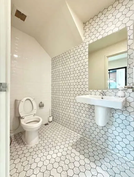 Townhouse for rent in Bang Phli, Samut Prakan - Bathroom with white hexagon tiles, toilet and wall-mounted sink.