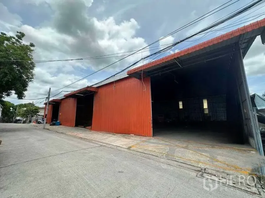 Warehouse for rent in Bang Kapi, Bangkok - Corner bay of the red warehouse showing drive-up access and a wide entrance for trucks.