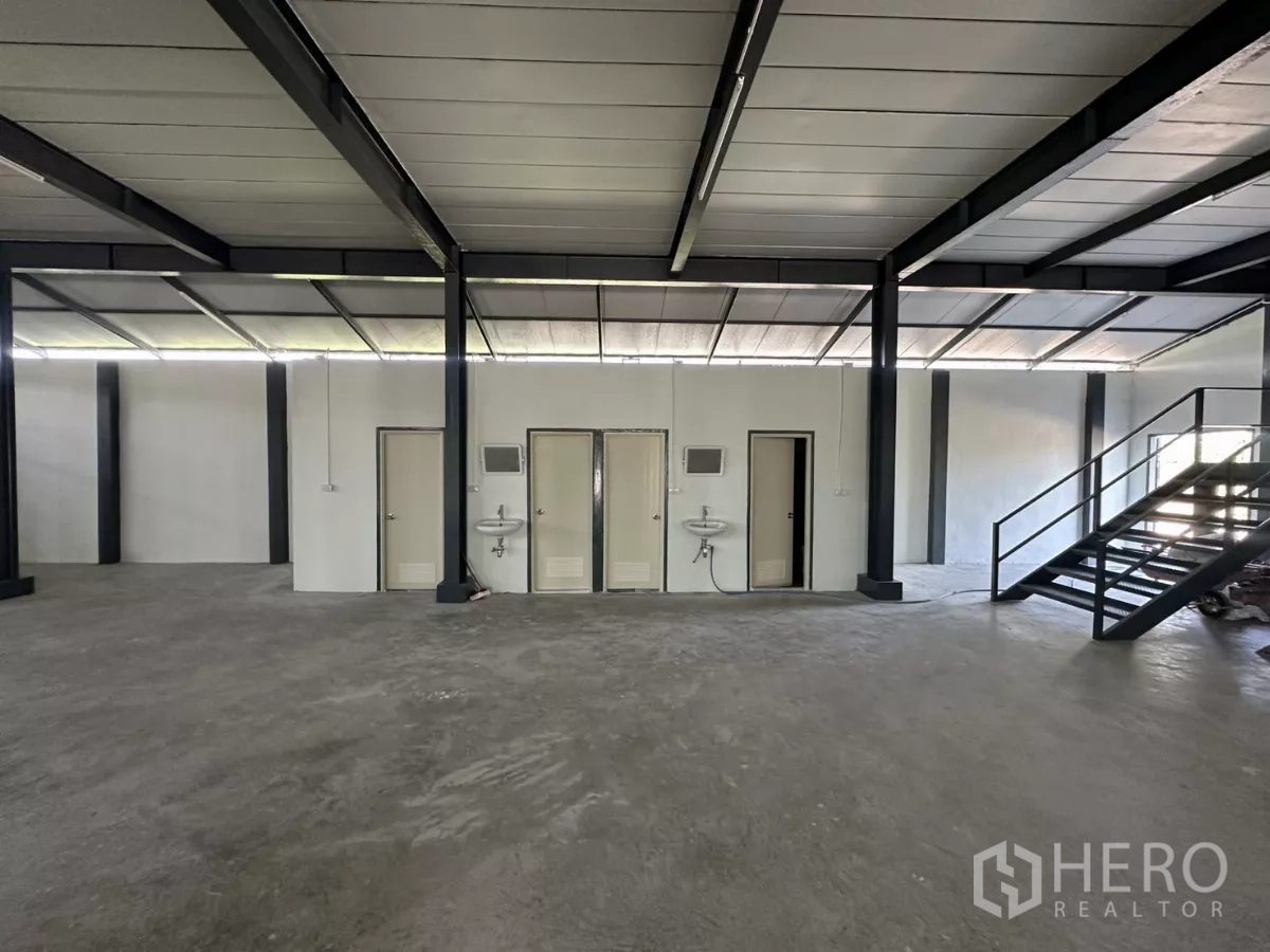 Warehouse for rent in Prawet, Bangkok - Amenities wall with multiple restroom doors and a metal staircase to the mezzanine.