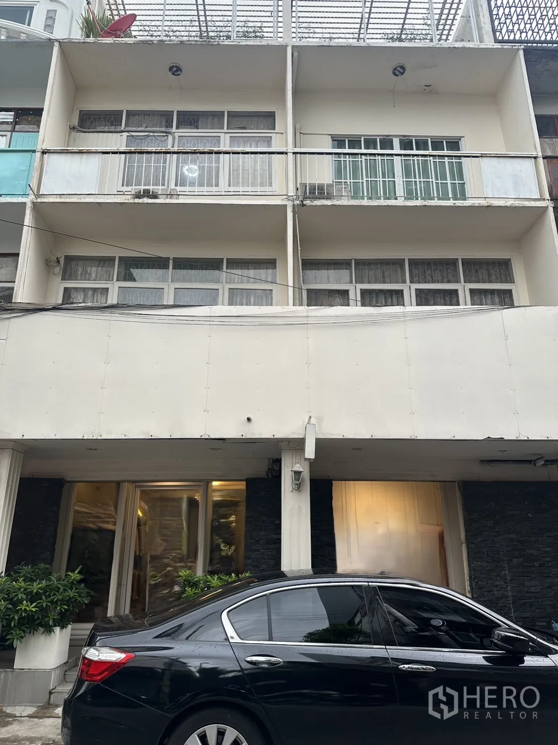 店屋 for sale in Watthana, Bangkok - 多层店屋正立面，带阳台，前方停有轿车。