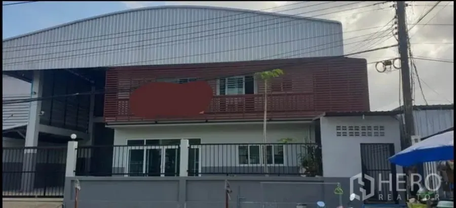 Warehouse for rent in Khlong Luang, Pathum Thani - Modern warehouse exterior with gated fence, two-storey office and metal cladding.