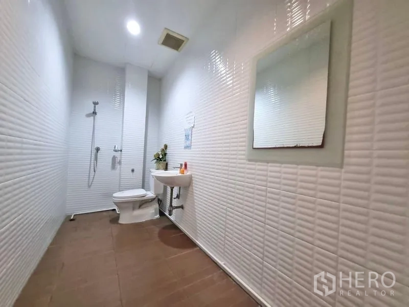 Shophouse for rent in Watthana, Bangkok - Clean restroom with shower, toilet, sink and white textured wall tiles.