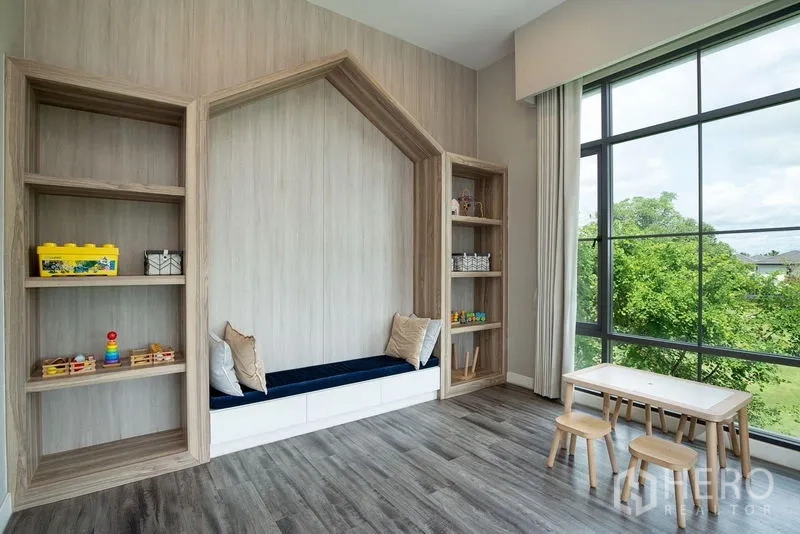Detached House for rent in Bang Phli, Samut Prakan - Family room with built-in wood shelving, bench seat and tall picture windows overlooking greenery.