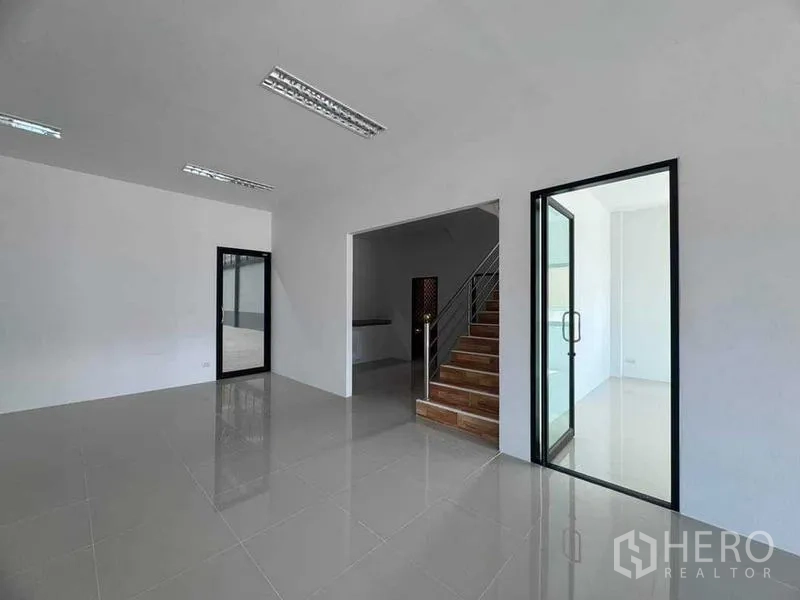 Factory for sale in Samut Sakhon - Ground-floor office with glass partitions and staircase leading to upper level.