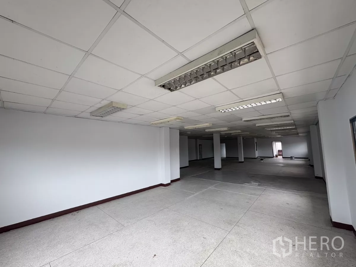 Factory for rent in Khlong Toei, Bangkok - Expansive office floor with drop ceiling and fluorescent fixtures.