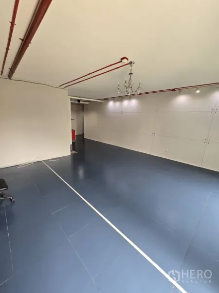 Office Space for rent in Watthana, Bangkok - Spacious office zone with chandelier, white panel wall, blue tiles, and ceiling sprinkler pipes.
