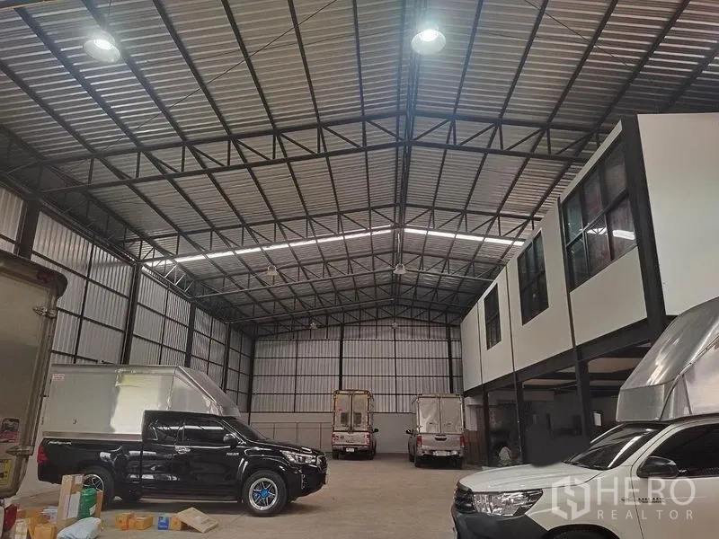 Warehouse for rent in Bang Khen, Bangkok - Night view of the warehouse interior with trucks and an elevated office block under a steel roof.