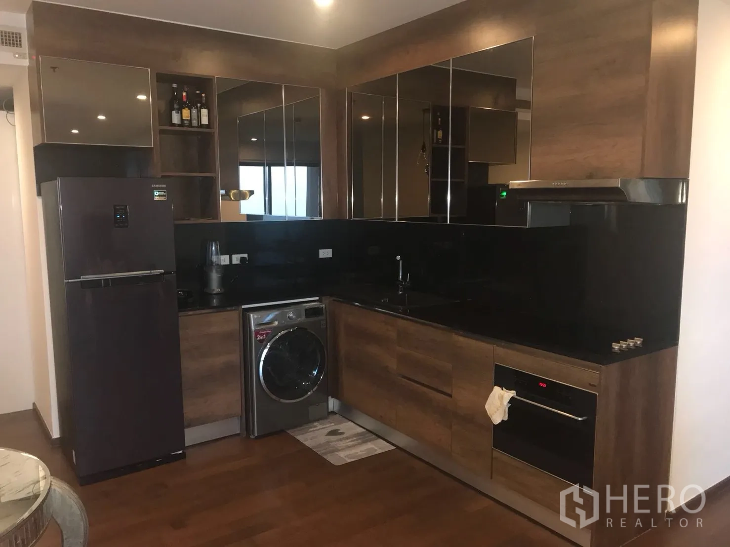 Condominium for rent in Khlong Toei, Bangkok - Modern kitchen with black granite countertops, built-in oven and washer.