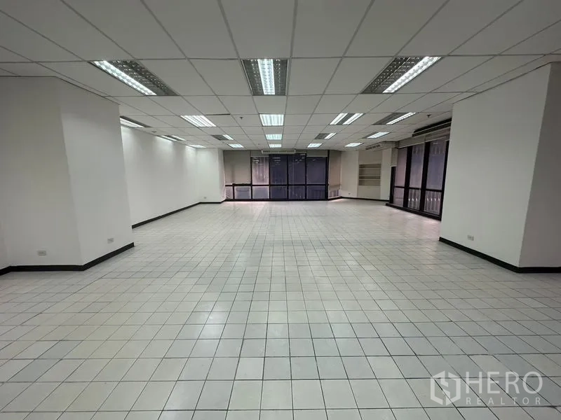Office Space for rent in Din Daeng, Bangkok - Large empty office space with white tiled flooring and full-length windows.