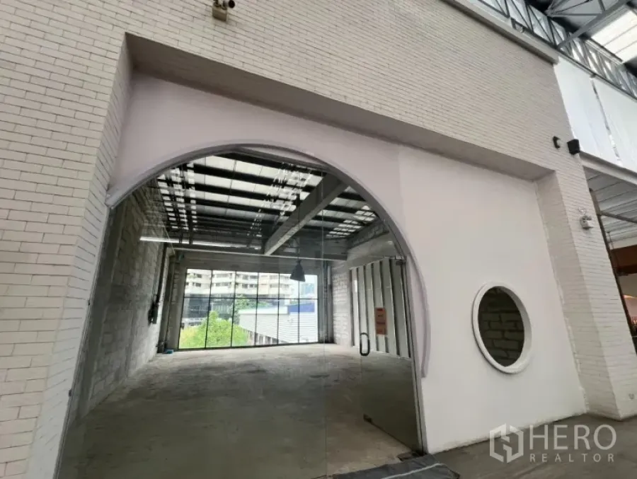 Retail Space for rent - Second-floor retail unit with arched glass entrance, white brick facade and round window in Khlong Toei.