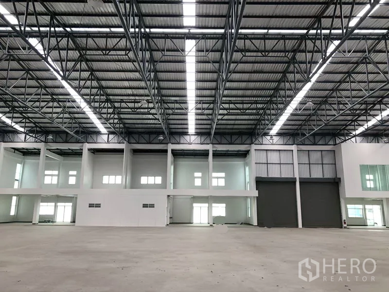 Factory for rent in Phra Nakhon Si Ayutthaya - Spacious warehouse interior with 9‑meter steel roof, skylights and large roller doors.