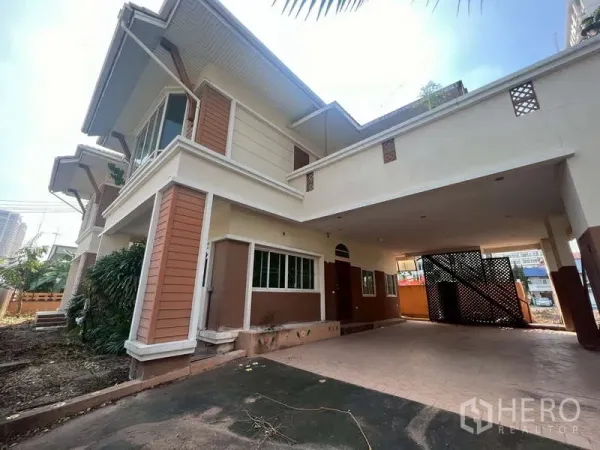 Detached House for rent in Watthana, Bangkok - Side view of the house showing covered parking area and ground space for a garden.