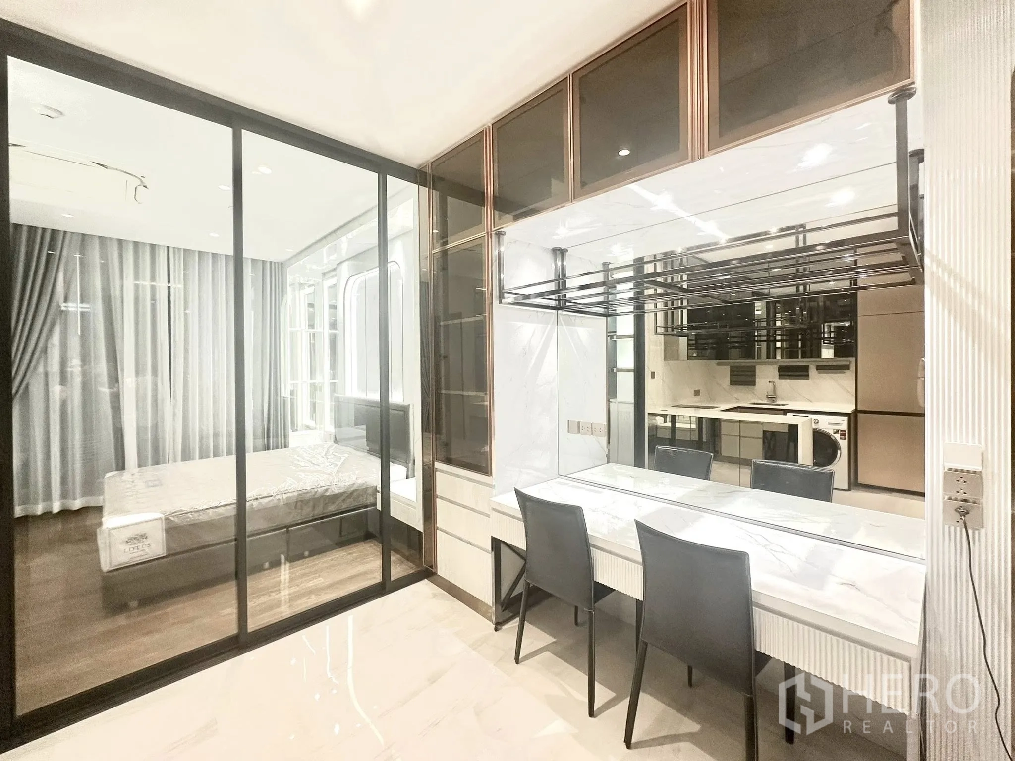公寓 for rent in Sathon, Bangkok - 玻璃隔断的卧室与带大理石餐桌和镜面墙的用餐区相连。