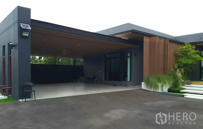Detached House for rent or sale in Lam Luk Ka, Pathum Thani - Contemporary single-storey house exterior with wide covered carport, wood slat accents and large windows.
