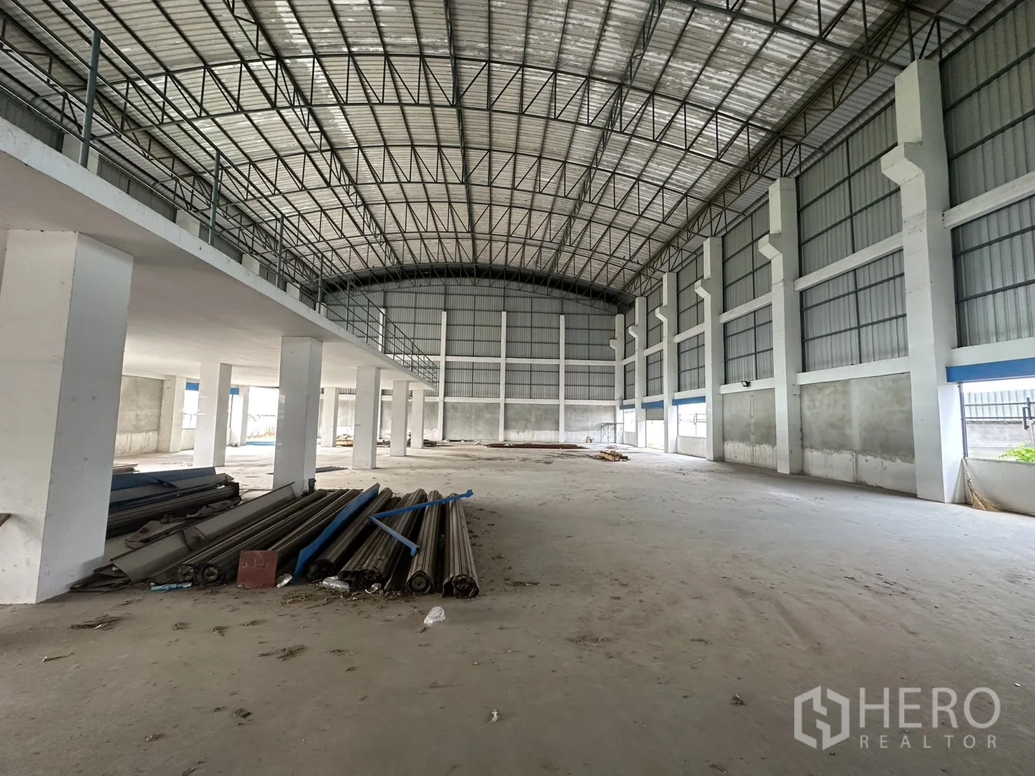 Factory for rent in Pak Kret, Nonthaburi - Spacious production floor with high clear span, steel truss roof and mezzanine platform on one side.