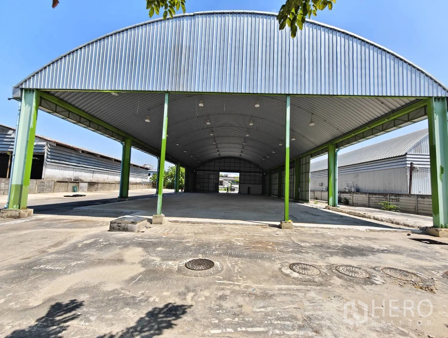 Warehouse for rent in Lak Si, Bangkok - Open-sided covered bay with high arched roof, steel columns, and overhead lighting.
