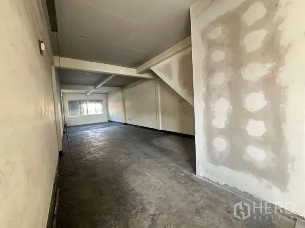 Office Space for rent in Phra Khanong, Bangkok - Deep workspace with patched drywall, exposed beams and a window at the far end.