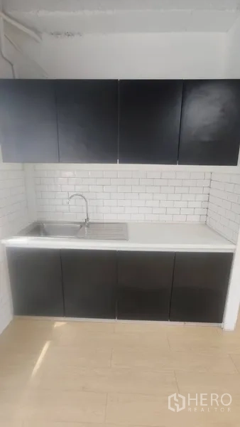 Office Space for rent in Pathum Wan, Bangkok - Pantry with black cabinets, stainless-steel sink and white subway tile backsplash.